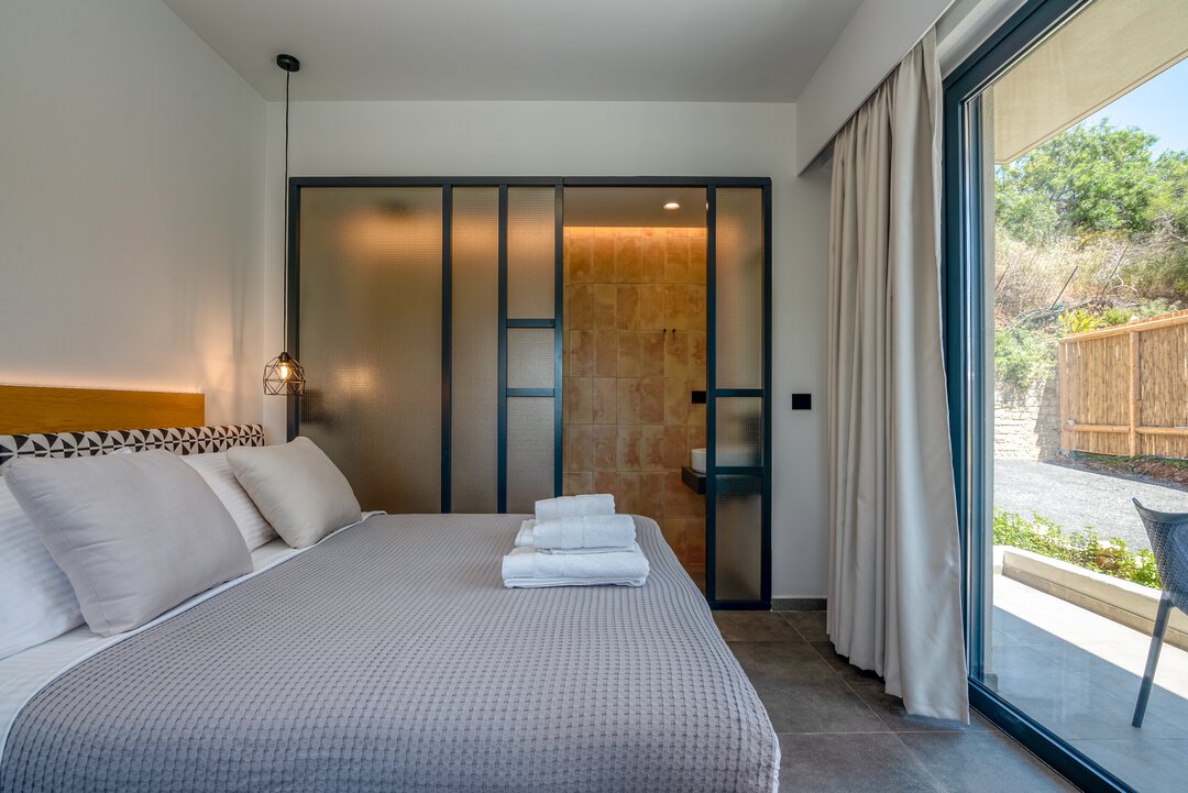 Peaceful bedroom with quality linens, designer pendant light, and calming neutral palette at Nusa Falassarna, Crete
