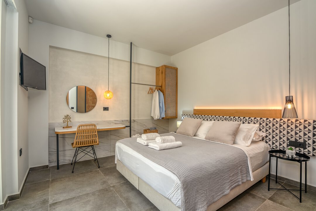 Elegant master bedroom with geometric headboard, ambient LED lighting, open wardrobe, and fresh towels at Nusa Balos villa near Balos Lagoon, Crete