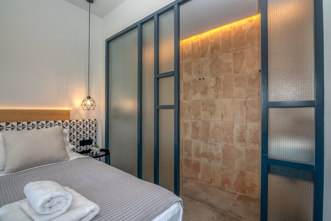 Contemporary guest bedroom with geometric headboard, quality linens, and modern furnishings at Nusa Balos villa, Crete